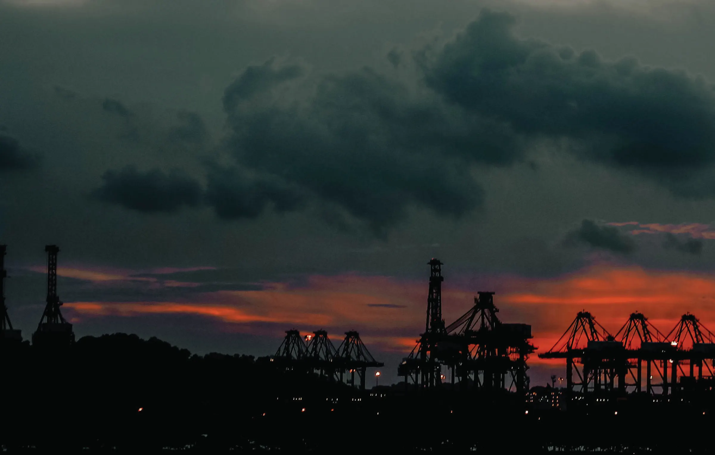 Port cranes silhouetted against a dramatic sunset